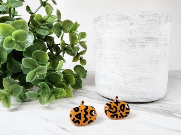 These polymer clay earrings are lightweight, eclectic and sure to make a statement. Just in time for Halloween! These stud earrings feature a bright orange pumpkin and a black abstract print. They are coated with resin for extra shine.